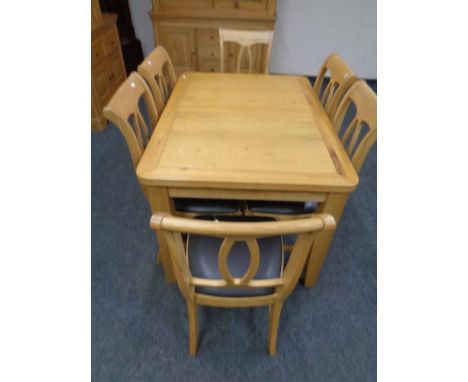 A contemporary light oak extending dining room table together with six chairs. 