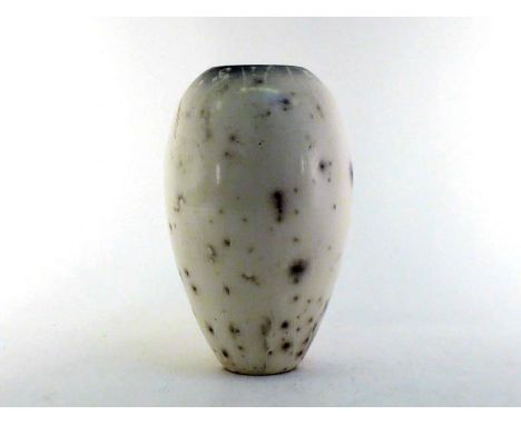 A tall elongated ovoid ceramic vase, the white body with speckled spread grey/black spots giving the impression of a bird's e