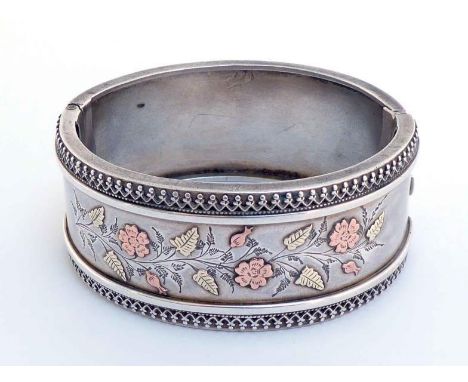 A Victorian silver bangle, unmarked, circa 1880, engraved and applied in two-colour gold with flowers and ferns, with decorat
