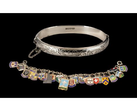 Silver Bangle with decorative engraved pattern to front, and safety chain; together with a charm bracelet with 26 tourist sou