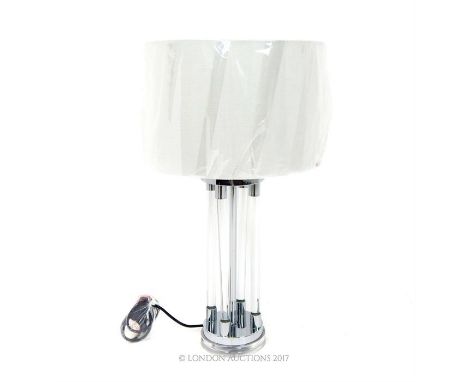 A contemporary architectural design table lamp, having an ivory coloured shade, with glass cylinders, raised on a circular ch