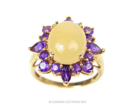 A fine, 14 ct yellow gold, jade and amethyst cluster ring, composed of a large, oval, claw-set  white jade cabochon, surround