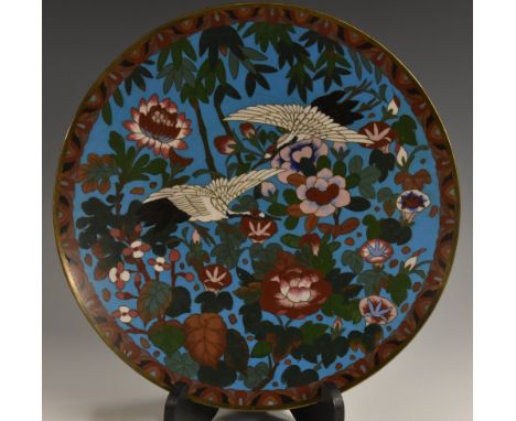 An Oriental cloisonné enamel circular charger, decorated in polychrome with kranes and blossoming chrysanthemums, on a pale b