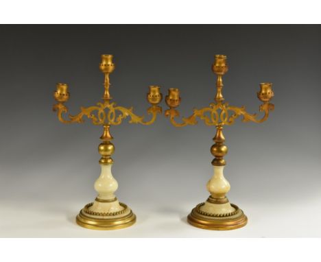 A pair of 19th century alabaster and gilt metal three-light candelabra, waisted sconces, engraved leafy scroll branches, knop