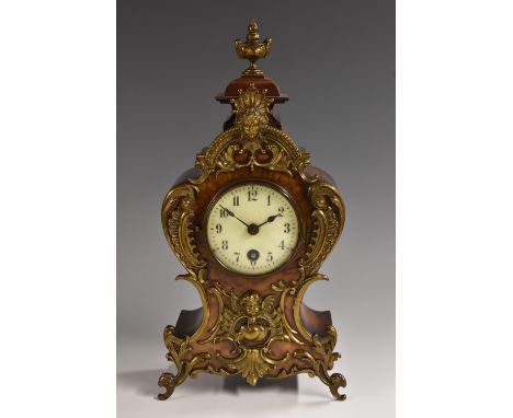 A German gilt metal mounted walnut mantel timepiece, cartouche shaped case crested by a brass flaming urn finial, 7.7cm round