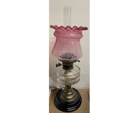 An oil lamp with clear glass reservoir and etched ruby glass shade