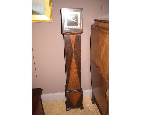 A grandmother clock in oak case, with silvered roman dial.
