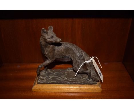 A cast resin bronze effect figure of a fox looking left over its shoulder, on oak plinth base.