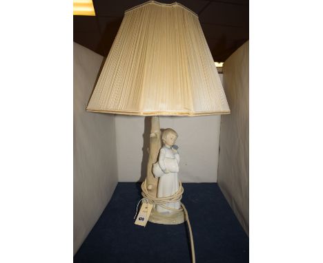 A Spanish Lladro style ceramic table lamp modelled as a small boy in a nightgown, with alarm clock next to a tree, the lamp f