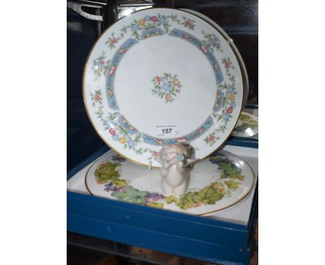 A Royal Worcester cake plate, Mayfield pattern, boxed; another, Vine Harvest pattern, boxed; a Nao model of a cherub with luc