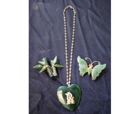 A green stone heart pendant, possibly jade, with applied initials RL, suspended from a gold plated chain necklace; similar ba