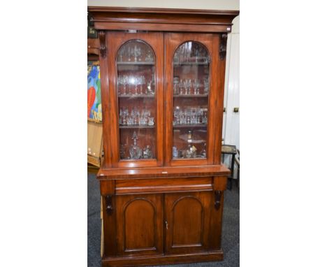 A late Victorian library bookcase, concave moulded cornice above a pair of glazed doors enclosing three shelves, the base wit