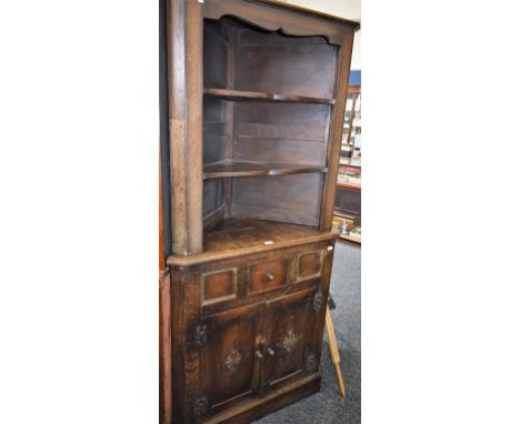 A 17th century style oak floor standing corner cupboard, shallow moulded cornice above two open shelves, the base with a cent