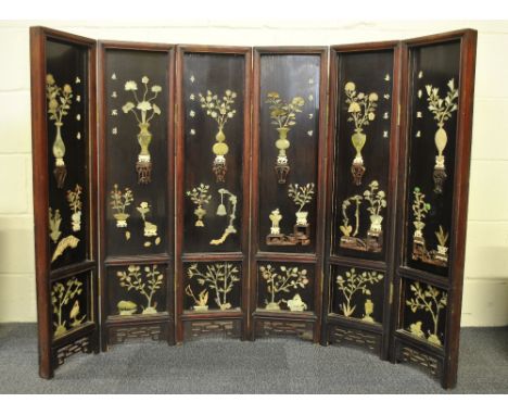 A superb 19th / early 20th century Chinese hardwood screen in six panels decorated in relief with jade and hardstone and hand