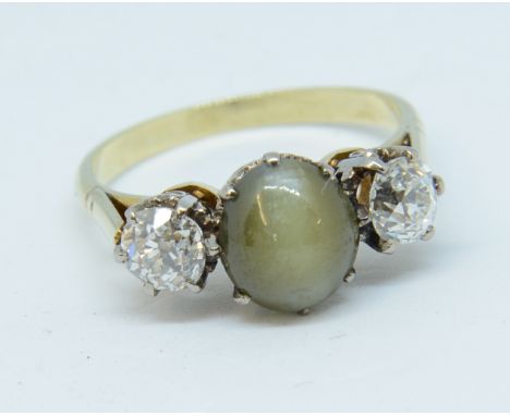 A three stone ring, set in unmarked yellow gold, the centre stone possibly 'Chrysoberyl'. size L.