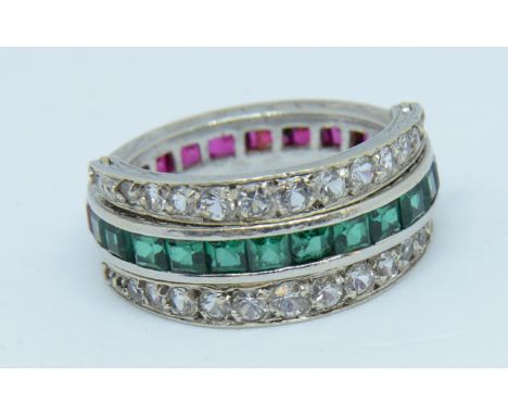 A white gold reverse ring set with channels of emeralds and rubies and diamond effect stones, size K.