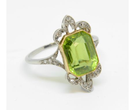 An antique peridot and diamond ring set in platinum and yellow gold, the octagonal old cut peridot approx 5cts with a diamond