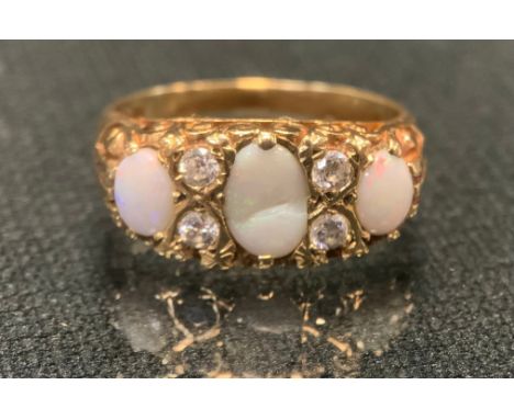 An opal and white stone ring, set with three oval opals each divided by a pair of white stones probably sapphires, 9ct gold s