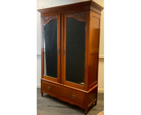 An late Victorian mahogany wardrobe, architectural pediment, pair of doors with carved panels above full length mirrors, sing