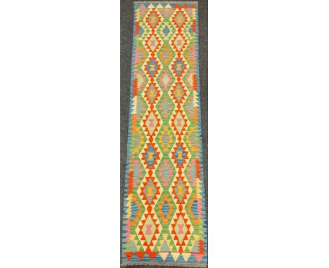 A Turkish Anatolian Kilim runner carpet / rug, woven in tones of blue, green, red, and cream, 290cm x 76cm. 