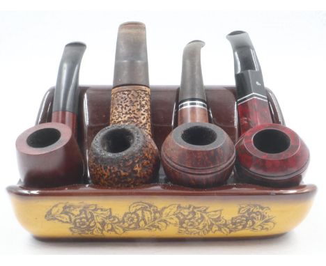 Four mixed smoking pipes including Petersons of Ireland and a meerschaum example, on a ceramic pipe rest. UK P&amp;P Group 2 