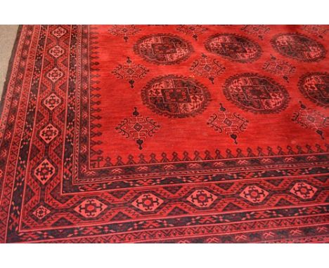 Wilton wool carpet, Tekke design on a red field, bordered outlines 440 x 320cm.