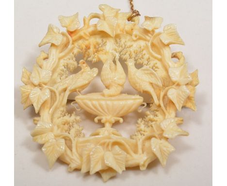 Carved ivorine brooch, decorated with birds drinking from a fountain within a vine surround, 6cm.