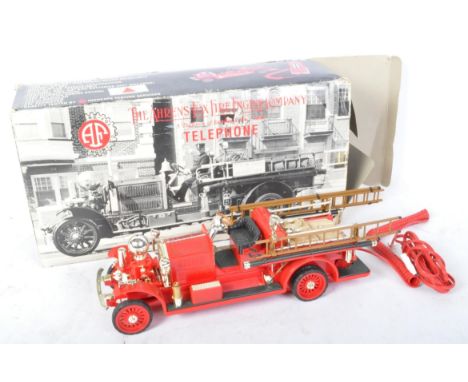 A vintage 20th century Ahrens-Fox Fire Engine Company telephone in the form of a red fire engine with wheels. Box measures 45