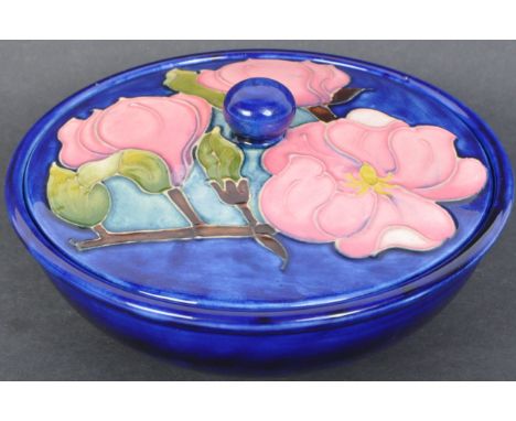 A vintage 20th century Moorcroft cobalt ground pot pourri / lidded dish in the "Magnolia" pattern being raised on a round foo