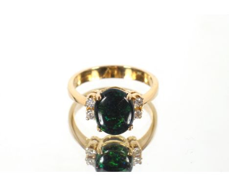 An 18ct gold opal and diamond set ring, ring size M. The large oval opal in raised four claw setting with two claw set brilli