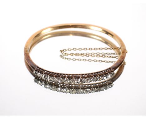 A yellow metal and diamond set bangle, the centre stone approx. 0.25carat flanked by fourteen graduated stones approx. 10gms 