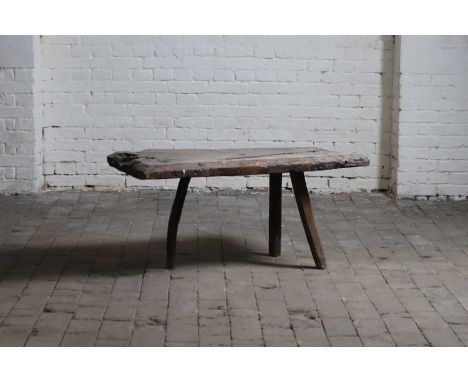 An oak estate-made pig bench, 19th century, the gnarled top with a bevelled edge and raised on three splayed legs,104cm wide4