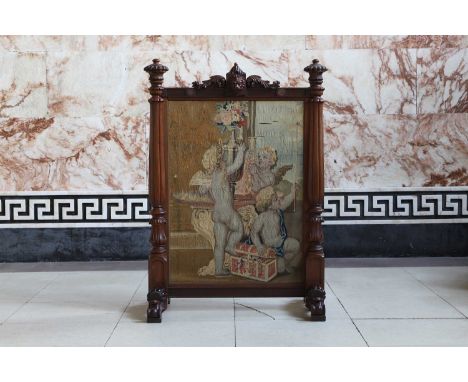 A William IV mahogany fire screen, centred with a Mortlake tapestry fragment depicting three mischievous putti, the heavily t