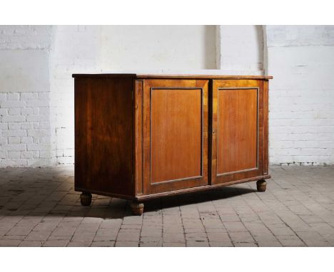 A Regency mahogany low press cupboard, the two panelled doors with cast-bronze beaded borders, enclosing two slides, a shelf 