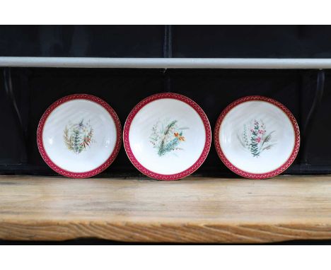 A Royal Worcester porcelain cake stand and two plates, each decorated to the centre with a floral spring, within a red-painte