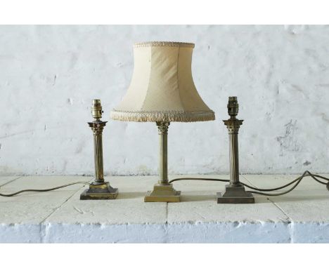 A set of three brass table lamps, 20th century, each reeded column surmounted with a Corinthian capital and raised on a squar