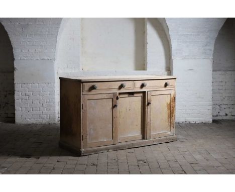 A pine dresser base, late 19th century, the two drawers with bun handles, centred with a sliding cupboard fitted with a reces