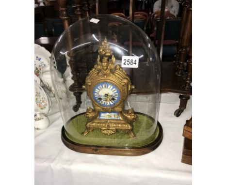 A French style mantel clock featuring porcelain face and panel under glass dome