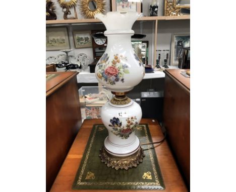 A floral overlaid white glass oil lamp style electric lamp
