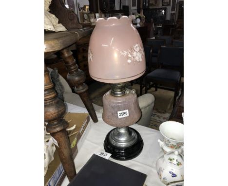 A 20th century oil lamp with pink glass shade and vessel