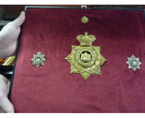 A Devonshire Ordinary Ranks Helmet Badge, two Devonshire Regiment cap badges and a dollar badge, mounted. 