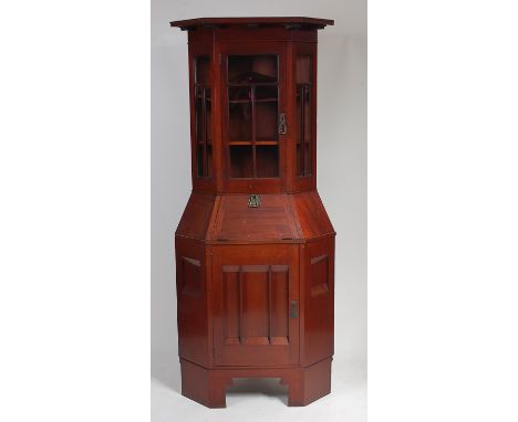 A Scottish School Arts & Crafts walnut freestanding corner cabinet, comprised of two sections, having glazed upper door with 