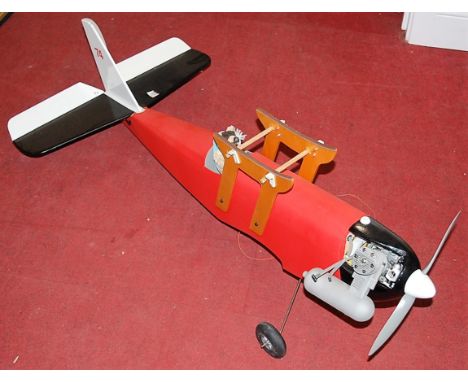 A part complete balsa wood model of a radio controlled petrol powered biplane comprising red fuselage with pilot and two jock