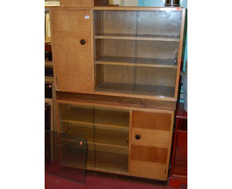 A pair of 1930s light oak low bookshelves, each having twin glazed sliding doors and single end panelled door, w.101cm; toget