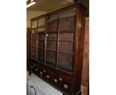 An antique mahogany double door glazed bookcase, having three short lower drawers on ogee bracket supports, width 126.5cm   C