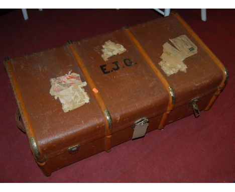 An early 20th century tan canvas, wooden and metal bound travelling trunk, having end carry handles 