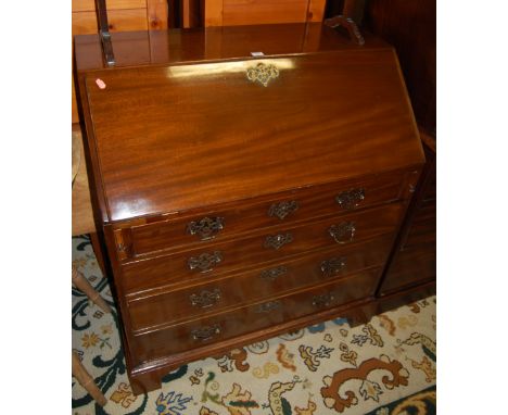 A George III mahogany slopefront writing bureau, having a fitted interior over four long graduated drawers to bracket support