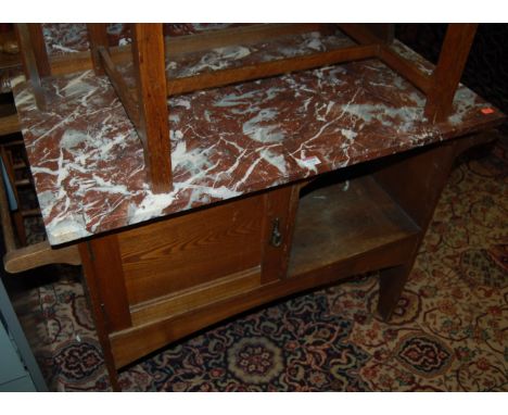 An Edwardian oak and red variegated marble topped washstand, having integral splashback, single cupboard door and open compar