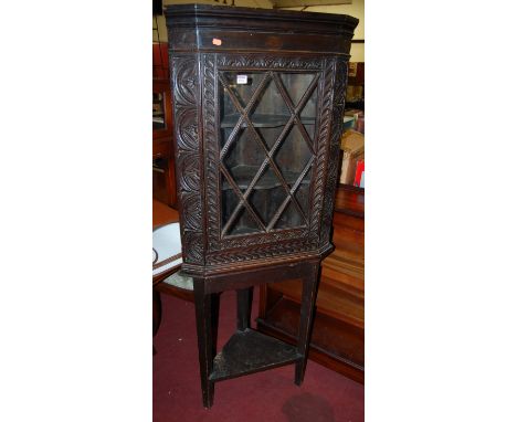 An antique low relief carved oak single door glazed corner cupboard, on later stand 