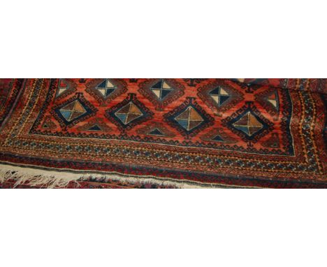 A Persian woollen carpet, the rust coloured field decorated with interlocking geometric medallions within multiple trailing b